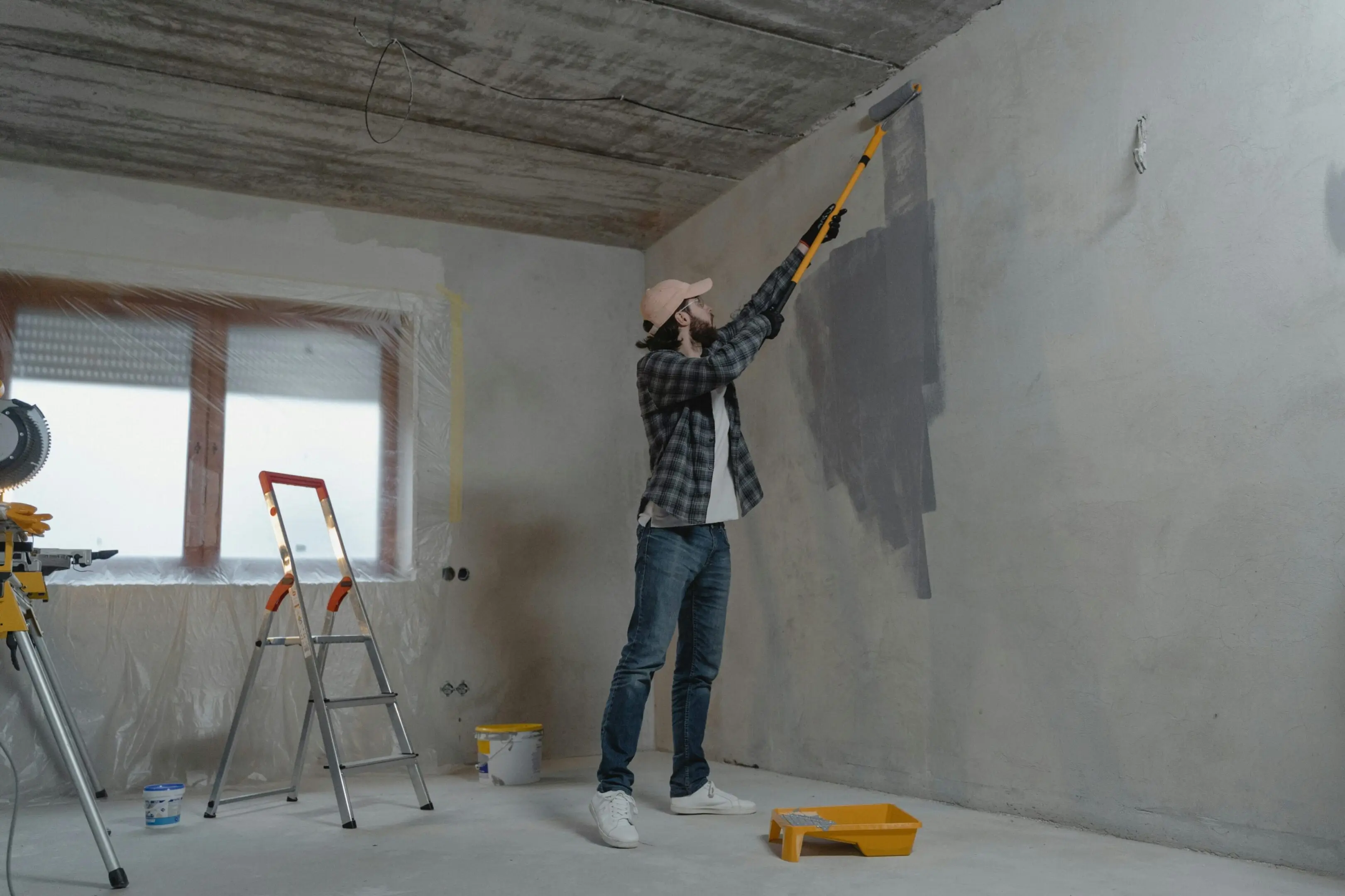 a man painting a wall with a roller brush